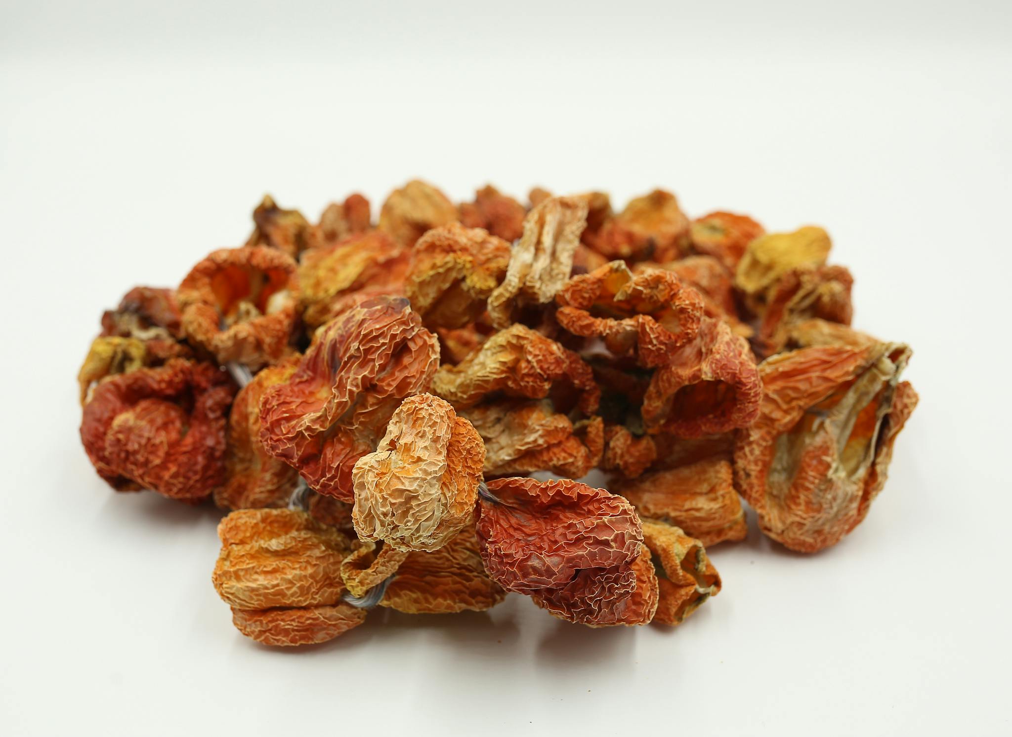 A heap of dried spicy peppers on a white background, ideal for food photography.