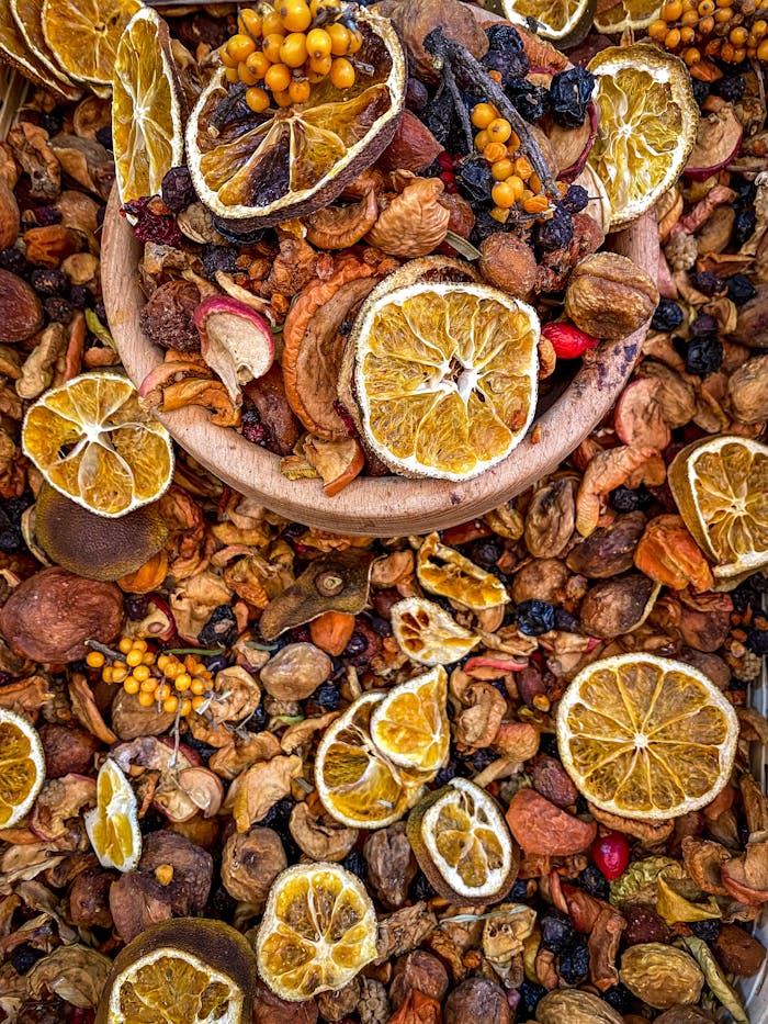 A colorful assortment of dried fruits including oranges, berries, and nuts displayed in a wooden bowl.
